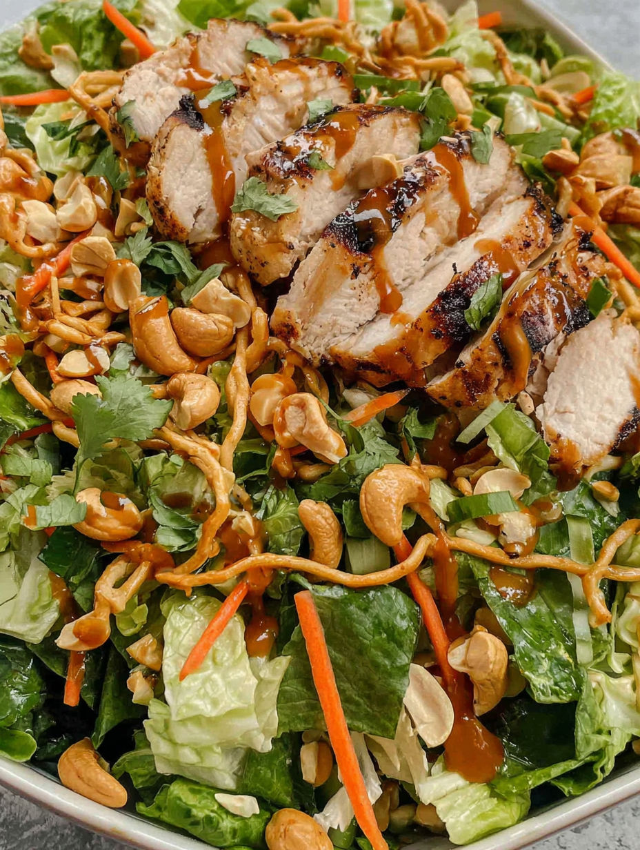 A salad with chicken, nuts, and sauce.