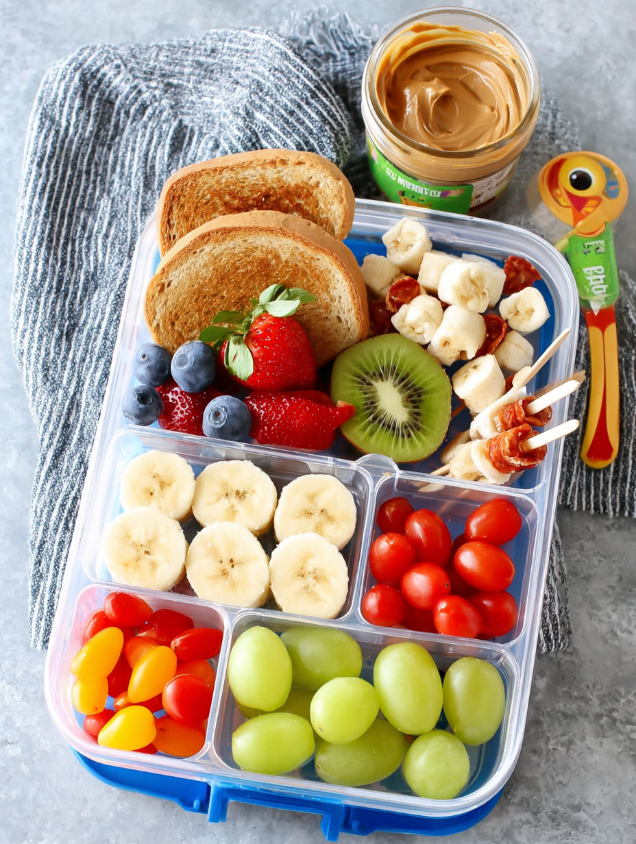 A variety of fruits and vegetables are arranged in a plastic container, including bananas, strawberries, kiwi, and tomatoes.