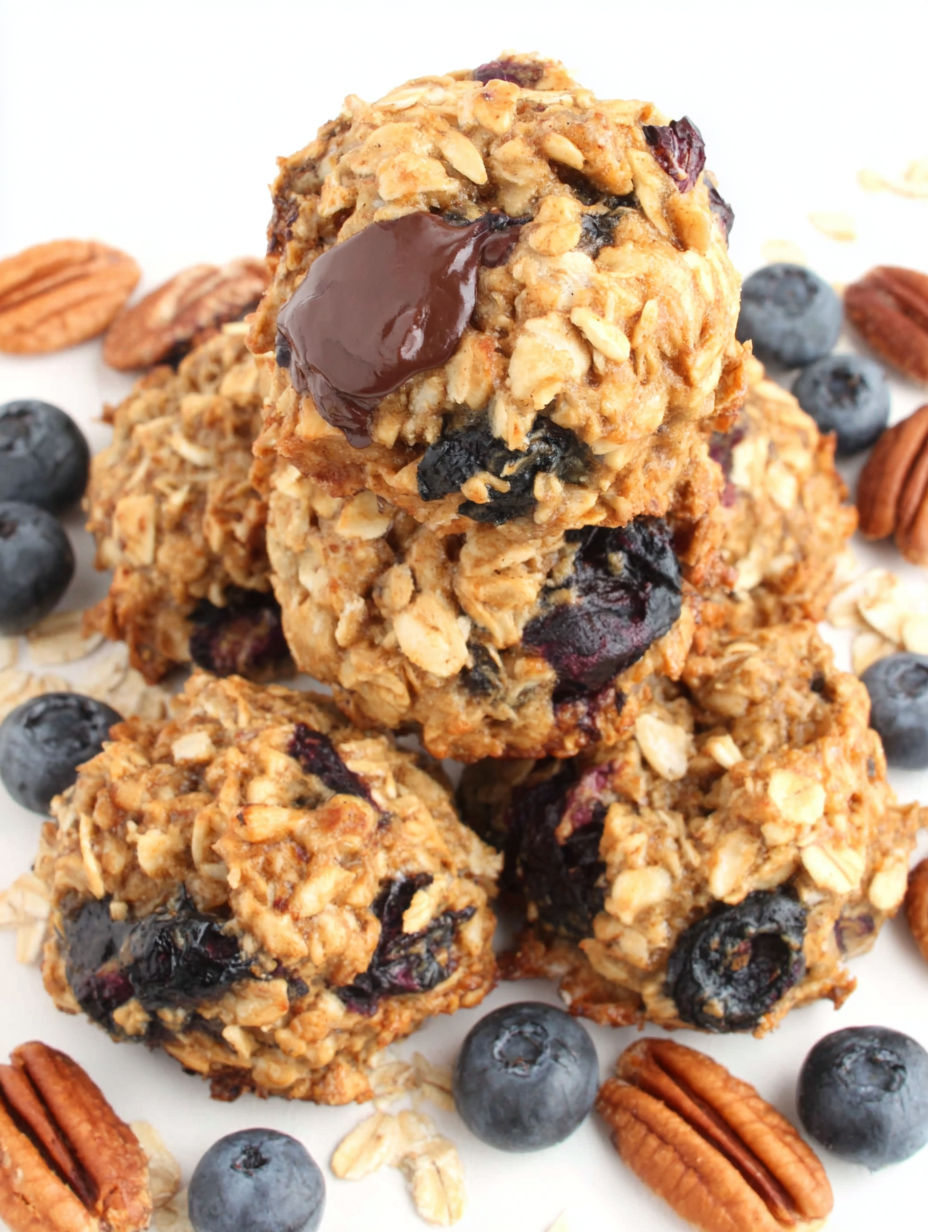 A stack of oatmeal cookies with chocolate drizzle and blueberries on top.