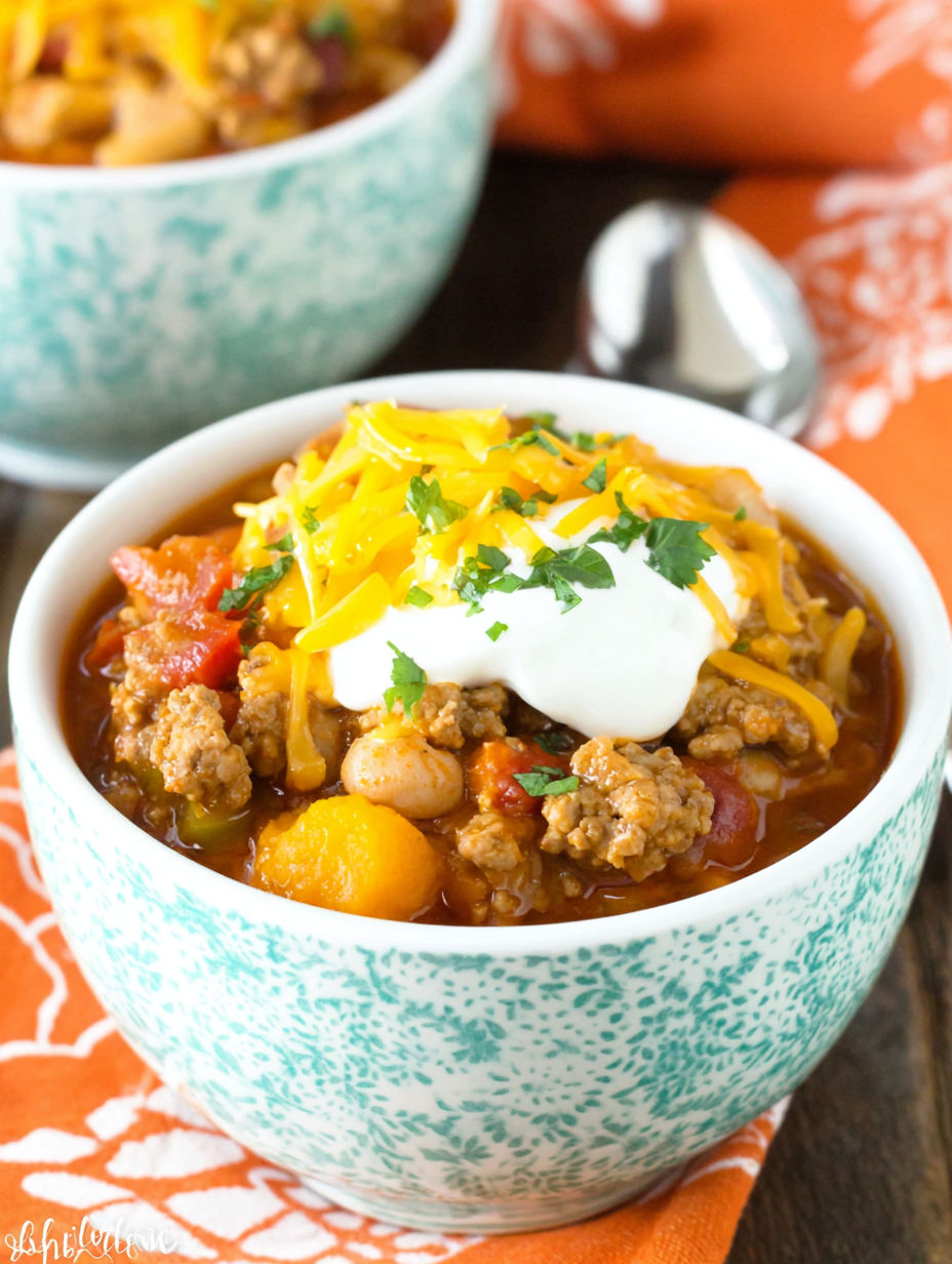 A bowl of chili with cheese and sour cream on top.