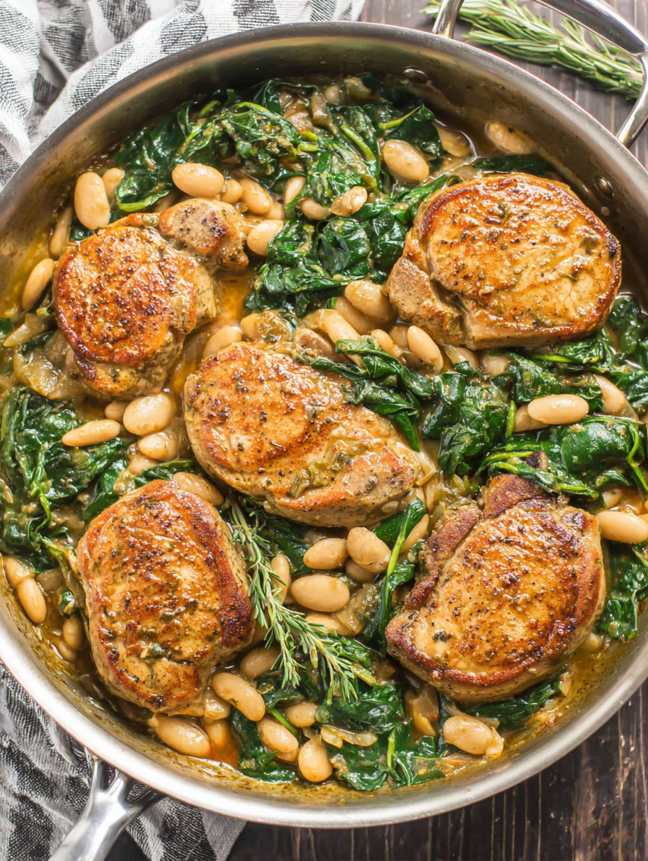 A skillet dinner with pork chops, white beans, and spinach.