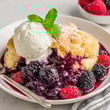 A bowl of berry cobbler with a scoop of ice cream on top.
