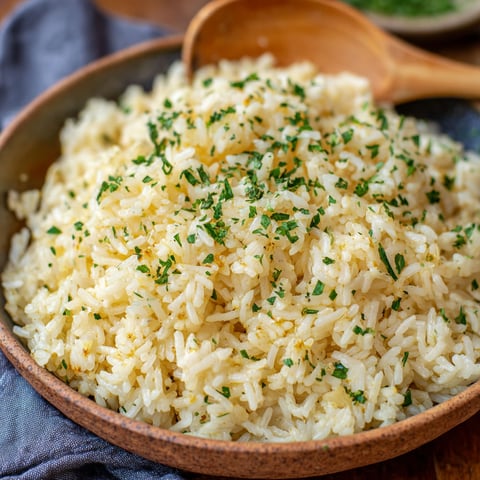 A bowl of rice with garlic butter and herbs.