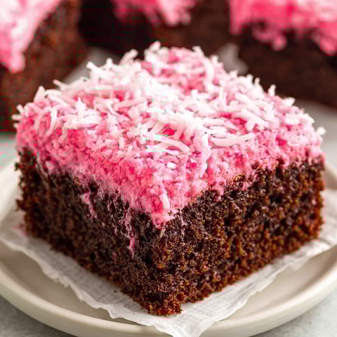 A slice of pink and brown cake with white powdered sugar on top.