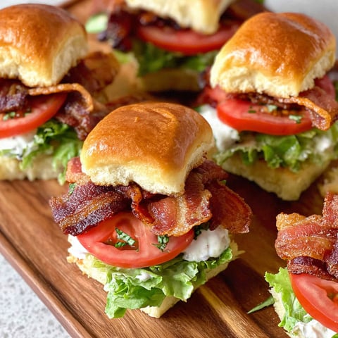 Bacon BLT sliders on a wooden platter.