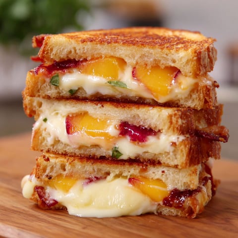 A stack of sandwiches with peaches and white cheese.