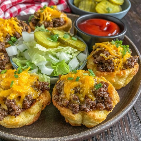 A plate of cheeseburger cups with lettuce and pickles.