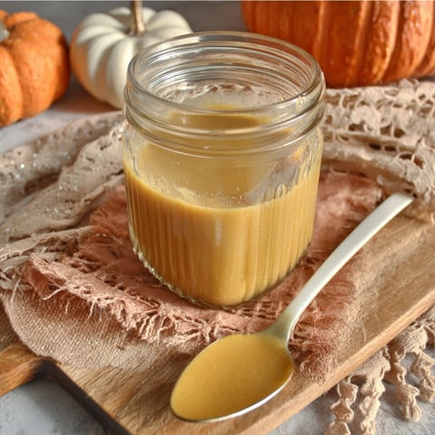A jar of pumpkin pie sauce on a wooden table.