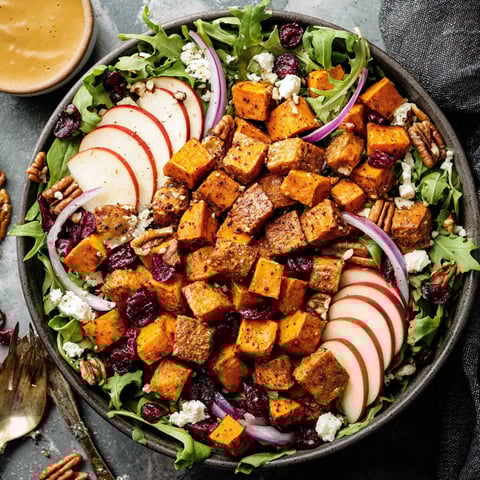A bowl of a salad with roasted sweet potatoes.