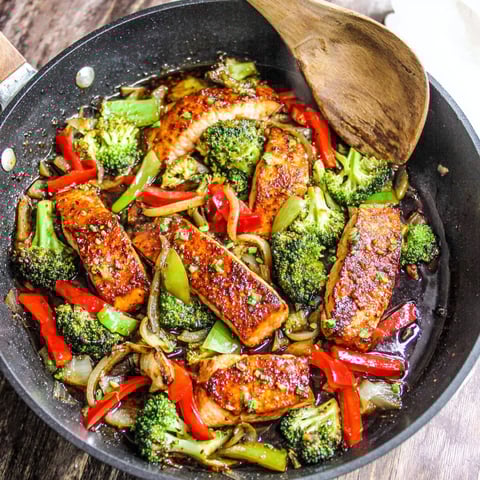 A pan of food with broccoli and red peppers.