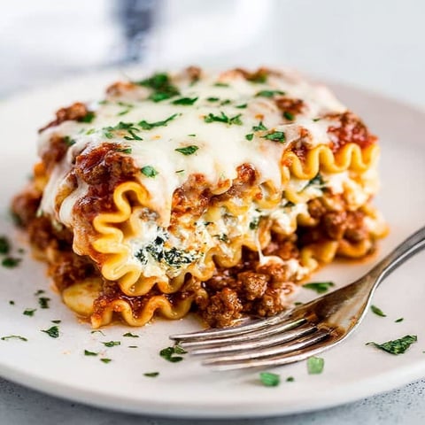 A plate of lasagna roll-ups with cheese and herbs.