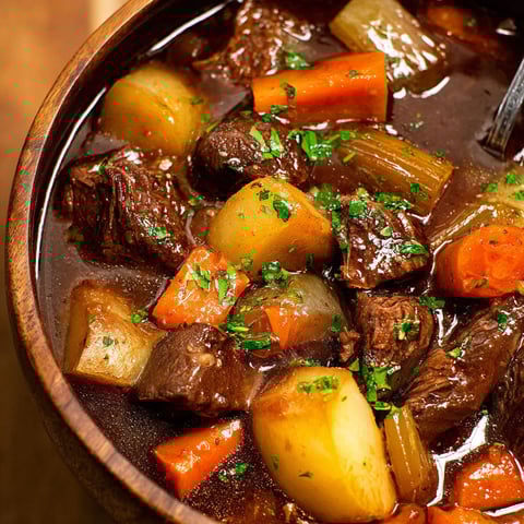 A bowl of beef stew with carrots and potatoes.