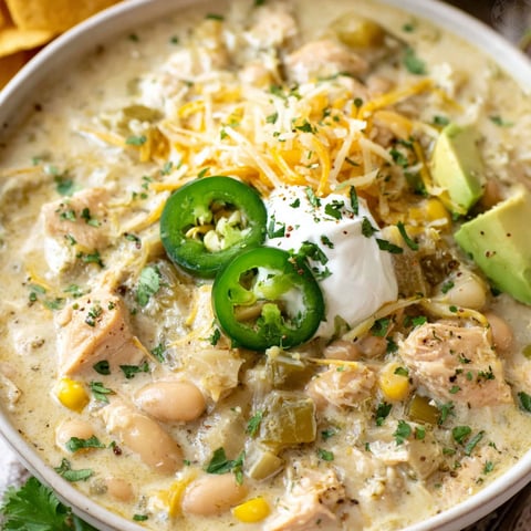 A bowl of creamy chicken chili with white cheese and green peppers.