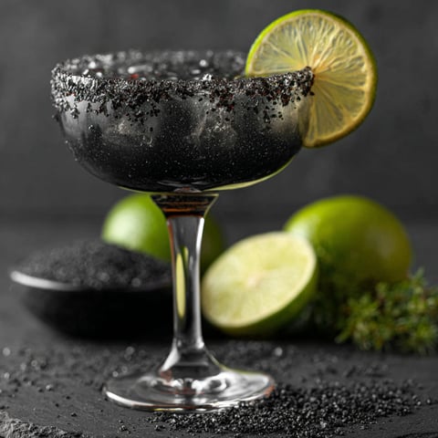 A glass of black margarita with a lemon wedge.