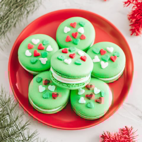 A plate of green cookies with hearts on them.
