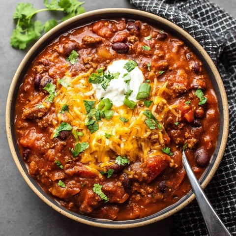 A bowl of chili with a spoon in it.