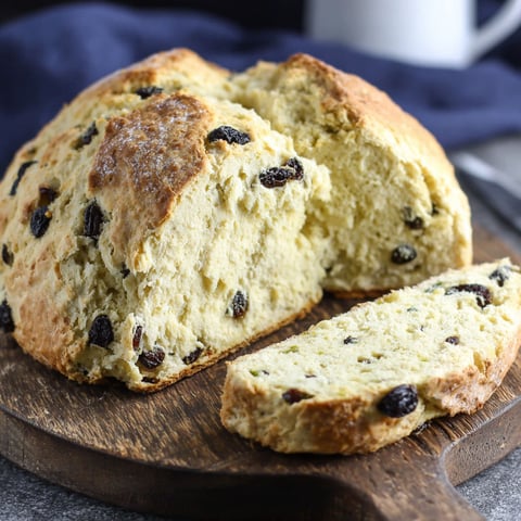 A slice of Irish soda bread on a wooden cutting board.