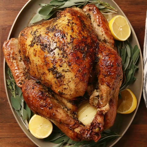 A roasted turkey with lemon wedges on top.