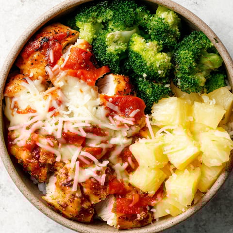 A bowl of food with chicken, broccoli, and pineapple.